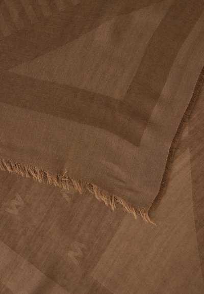 Tissu marron avec un motif géométrique subtil et un bord effiloché, montrant une texture douce et des plis qui se chevauchent.
