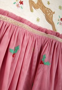 Rosa Tüllrock mit bestickten Stechpalmen- und Blumendesigns, verziert mit einem funkelnden goldenen Taillenbund und einer weichen, strukturierten Oberfläche.