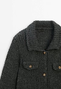 Cardigan en maille épaisse gris foncé avec col large et fermetures à boutons dorés sur le devant et les poches à rabat.