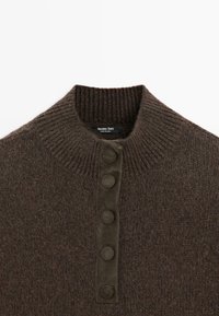 Maglione marrone lavorato a maglia con collo a coste e cinque bottoni lisci lungo la patta frontale. Etichetta visibile all'interno del collo.