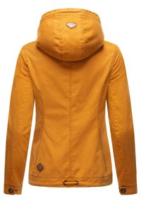 Žlutá bunda s kapucí, vyrobená z texturované tkaniny, s prošitými švy, nastavitelnou šňůrkou v pase a logem na zadní straně.