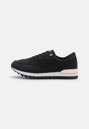 Czarny niski sneaker z teksturowaną tkaniną, oczkami i akcentem na pięcie w kolorze różowego złota, białą środkową podeszwą i żłobioną czarną podeszwą zewnętrzną.