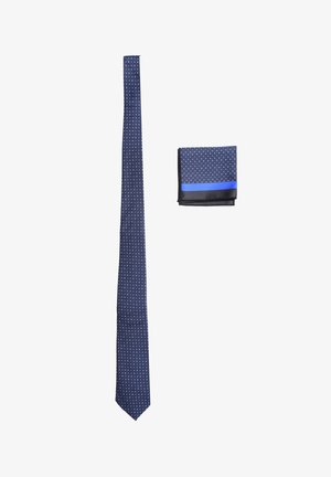 Cravatta navy con pois bianchi, con punta appuntita, abbinata a un fazzoletto da taschino coordinato con una striscia blu e bordo nero.