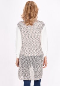 Cardigan lungo fino al ginocchio realizzato in maglia testurizzata nei colori rosa chiaro, grigio e bianco. Presenta un retro solido e maniche lunghe con polsini abbottonati.