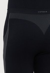 Zwarte leggings met een gladde textuur, voorzien van een contrasterend grijs gaaspaneel, geometrisch patroon en een elastische tailleband voor comfort.