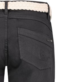 Black denim pants feature a braided cream belt, with a distinctive angled back pocket and subtle textured finish.