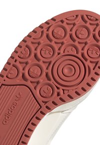 Adidas sneaker sula i röd gummi med cirkulärt mönster, som har upphöjda logotyper och ränder. Texturerad med släta och räfflade sektioner.