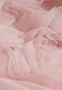 Mehka rožnata tila tkanina z lahkotno, prosojno teksturo, ki ima nagubane plasti in fino mrežasto strukturo.