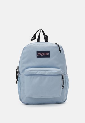 Zaino Jansport blu chiaro con scomparto principale con zip, tasca frontale con zip e tasca laterale in rete. Tessuto durevole, forma rettangolare.