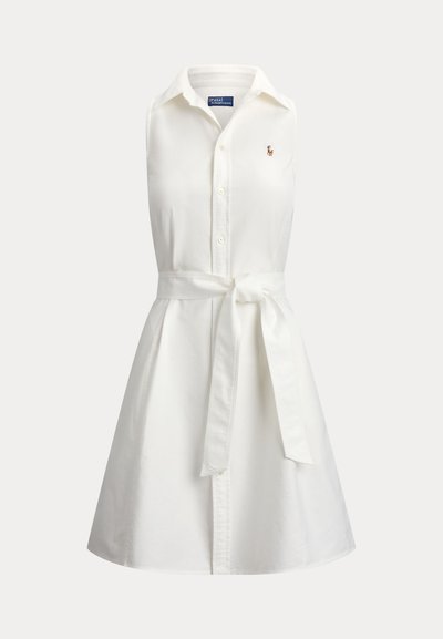 Robe chemise blanche sans manches avec col, boutons sur le devant, ceinture à nouer à la taille et petit logo brodé sur la poitrine.