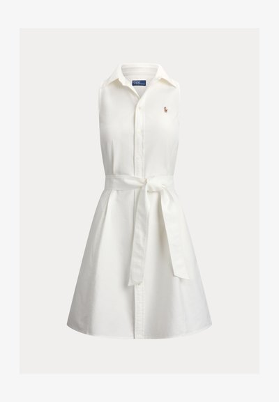 Robe chemise blanche sans manches avec col, boutons sur le devant, ceinture à nouer à la taille et petit logo brodé sur la poitrine.