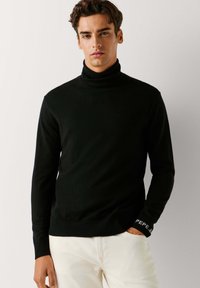 Maglione a collo alto di colore nero realizzato in tessuto morbido, con maniche lunghe e design aderente. Il polsino presenta un dettaglio di branding bianco "PEPE JEANS".