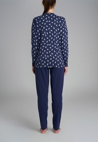 Set di pigiama blu navy composto da una maglietta a maniche lunghe con motivo floreale bianco e pantaloni abbinati in tinta unita blu navy. Tessuto morbido, vestibilità comoda.