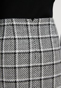 Black and white checkered skirt with textured fabric, featuring a fitted waist and a discreet zip closure.