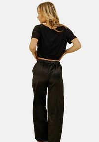 Top noir court à manches courtes ; pantalon noir à jambes larges légèrement texturé avec une taille élastique. Design simple et ajusté.