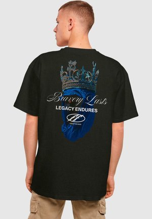 Svart bomull t-skjorte med grafikk av et blått hjerte og krone, med teksten "Bravery Lasts" og "LEGACY ENDURES" i hvitt.