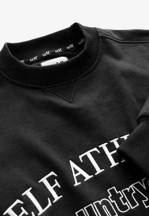 Schwarzer Pullover mit geripptem Rundhalsausschnitt, mit weißem gesticktem Text "SELF ATHLETE" und "Land" auf der Vorderseite. Glatte Textur.