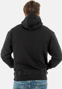 Schwarzer Kapuzenpullover aus weichem Material. Verfügt über eine große Kapuze, lange Ärmel und einen gerippten Saum. Basis- und Casual-Design ohne sichtbare Logos.