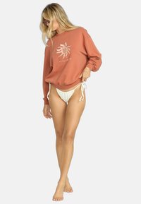 Rustfarget genser med solgrafikk og merkevarelogo; lett materiale; kombinert med hvite justerbare bikinitruser, minimalistisk design.