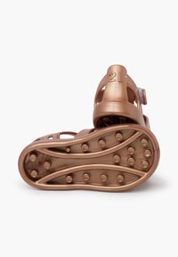 Bronzefarvet sandal med en glat plastikmateriale, åben design og struktureret sål med runde grebsmønstre, der har en nummereret rem.
