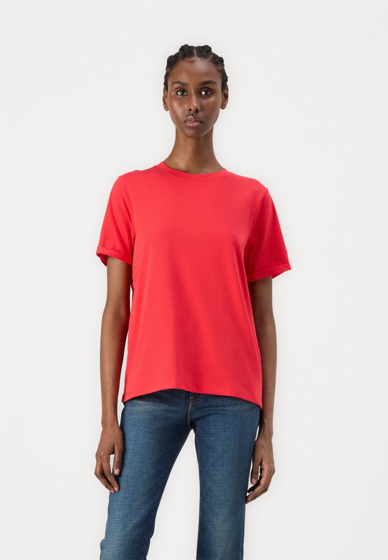 Rød t-skjorte med korte ermer i en myk bomullsblanding, med rund hals og en avslappet passform, kombinert med blå denimjeans.