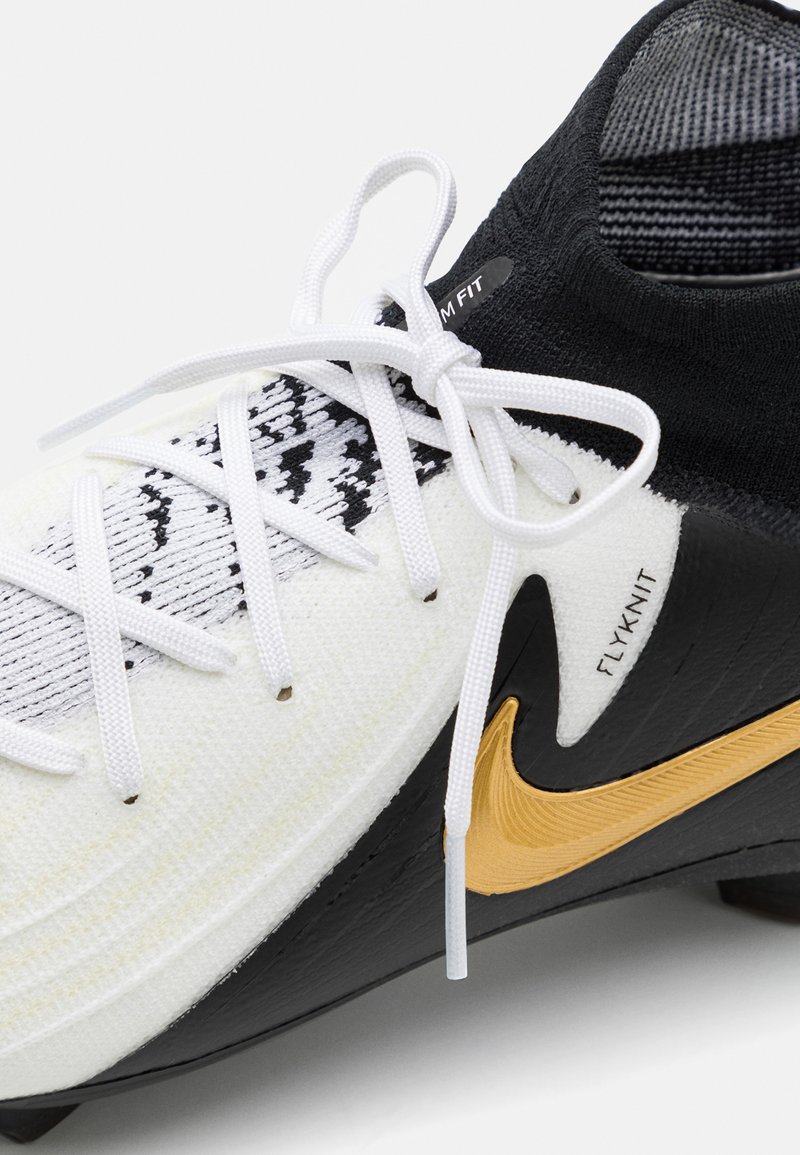 Scarpa da calcio Nike con tomaia bianca e nera, materiale in maglia testurizzato, dettagli neri, logo dorato e lacci bianchi.