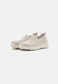 Baskets légères couleur beige clair à enfiler, avec une tige en maille texturée, un bout rond, une semelle rembourrée et une petite languette au niveau du talon.