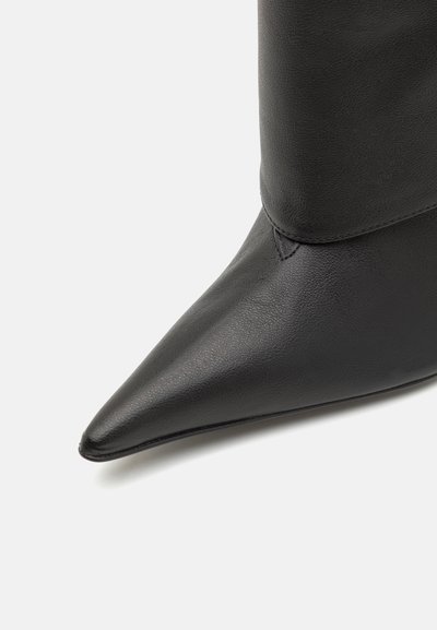 Fekete bőr bokacsizma hegyes orral, sima textúrával és illeszkedő szárával. Minimális varrási részletek és elegáns design.