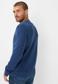 Blauwe gebreide trui met een ronde hals, geribde manchetten en zoom. Textuurstof en zijsplitsen voegen detail toe. Draag met denim jeans.