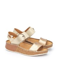 Sandali oro e crema con fibbia tonda, soletta in sughero e dettagli cuciti. Design open-toe con suola piatta in gomma.