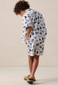 Set van een witte korte mouwen overhemd en shorts met marineblauwe tropische patronen. Gemaakt van lichte stof met een ontspannen pasvorm.