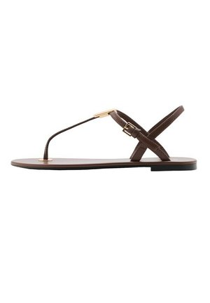 Sandalo piatto marrone con sottili cinturini, un passante per l'alluce e una fibbia dorata sul lato, mostrato su uno sfondo bianco.