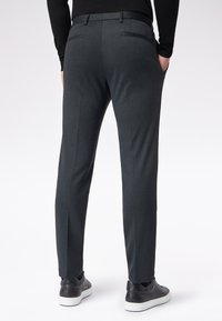 Dopasowane szare spodnie wizytowe o gładkiej teksturze, z dwiema tylnymi kieszeniami i slim fit, w połączeniu z eleganckimi czarnymi trampkami.