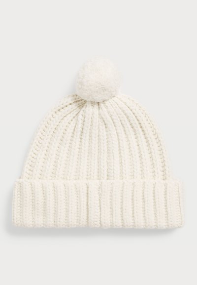 Knit balts cepure ar teksturētu ribu dizainu un pom-pomu augšpusē. Mīksts materiāls, kas piemērots aukstam laikam.