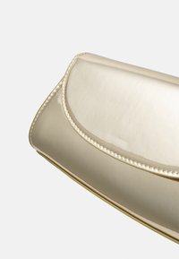 Clutch metallico dorato con una superficie liscia e lucente, una patta rotonda e cuciture in contrasto lungo i bordi. Design leggero.