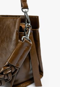 Bolso de mano de cuero marrón con una textura suave, un acento trenzado y herrajes plateados en la correa ajustable y el cierre.