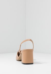 Beige heeled sandal with a square toe, adjustable ankle strap, and chunky heel. Smooth synthetic material with a matte finish.