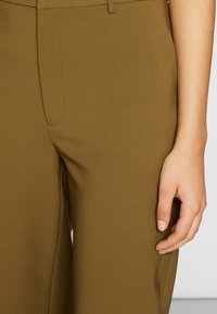 Olivgrön skräddarsydda byxor i slätt material, med flat front, sidfickor och en smal, rak passform.