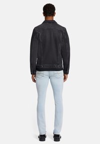 Svart denimjacka med krage, knäppning fram och två sidofickor. Ljusblå slim-fit jeans med kontrasterande sömmar.