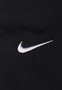 Black fabric with smooth texture featuring a prominently embroidered white Nike swoosh logo on the left side.