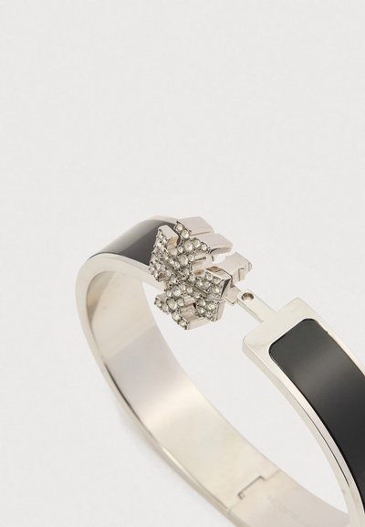 Bracelete prateado e preto com um fecho articulado, apresentando um pingente em forma de cruz incrustado com pequenas pedras preciosas transparentes.