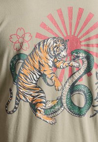 Tigre et serpent enlacés dans un combat, explosion solaire rouge et contour de fleur de cerisier en arrière-plan sur un tissu beige.
