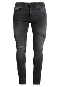 Jeans negros de corte slim con detalles desgastados, que presentan desgarros desflecados en las rodillas y un ligero desvanecimiento, fabricados en tejido de mezclilla.