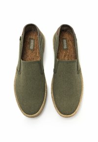 Chaussures vertes à enfiler avec une tige en toile texturée, semelle intérieure en liège naturel et semelles en jute tressé. Pas de matériel ou de motifs visibles.