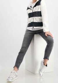 Vit och mörkgrön randig zip-up jacka med texturerat tyg, ihopparad med grå skinny jeans och silvriga högskor.