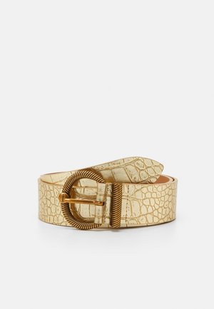 Złoty pasek ze skóry z wzorem krokodyla, z teksturowaną, skręconą, owalną metalową klamrą, zwinięty na białym tle.