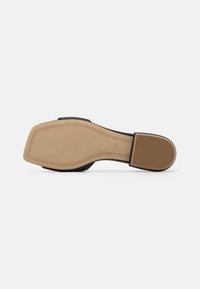 Suela de zapato negra con una base de goma beige lisa. Presenta secciones de agarre texturizadas, costuras limpias y una forma ligeramente curvada.