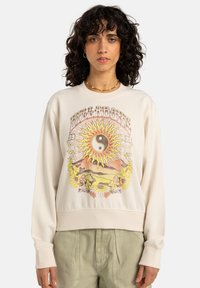 Gräddfärgad sweatshirt med grafiskt tryck som föreställer en sol, yin-yang-symbol och blommönster. Ribbat i ärmsluten och nederkant.