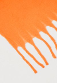 Πορτοκαλί μάλλινο κασκόλ με κρόσσια στα άκρα, που παρουσιάζει απαλή υφή και ζωντανό χρώμα, απλωμένο επίπεδο σε λευκό φόντο.