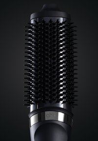 Zwarte ronde borstel met rubberen grip en plastic haren, voorzien van een glanzende metalen band met "ghd" merknaam. Textuur detail op het oppervlak.